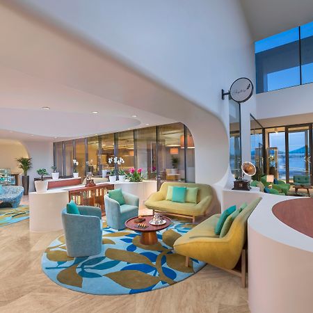 The Retreat Palm Dubai Mgallery By Sofitel Esterno foto The photo depicts a modern and stylish interior space, likely a lobby or lounge area. It features a variety of seating arrangements, including colorful chairs and a couch, all arranged around a central coffee table. The floor is adorned with a large,