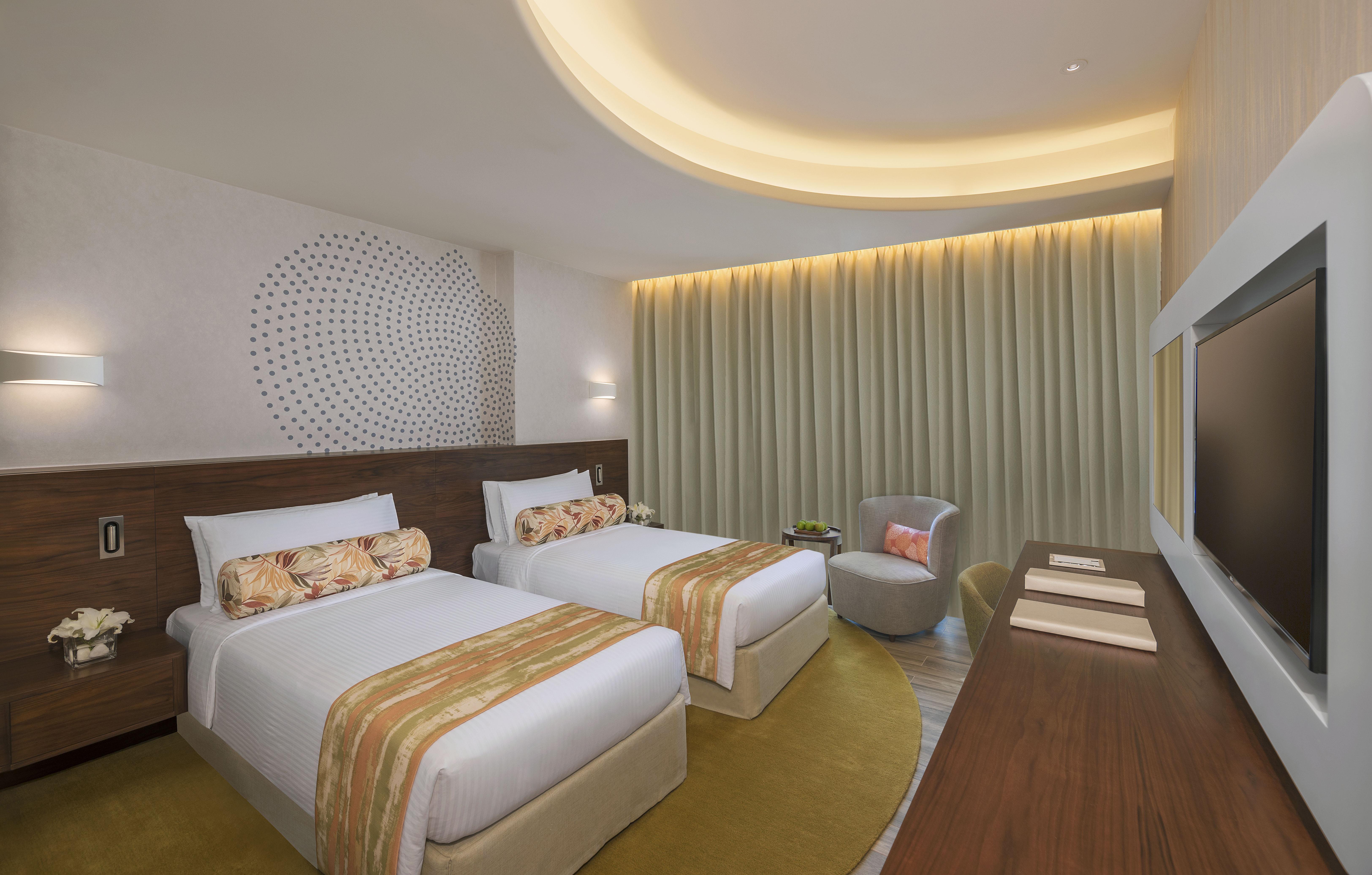 The Retreat Palm Dubai Mgallery By Sofitel Esterno foto The photo displays a modern hotel room featuring two separate beds with stylish headboards and decorative throw pillows. The beds are neatly arranged with crisp white linens and colorful accent throws. Behind the beds, there is a decorative wall with