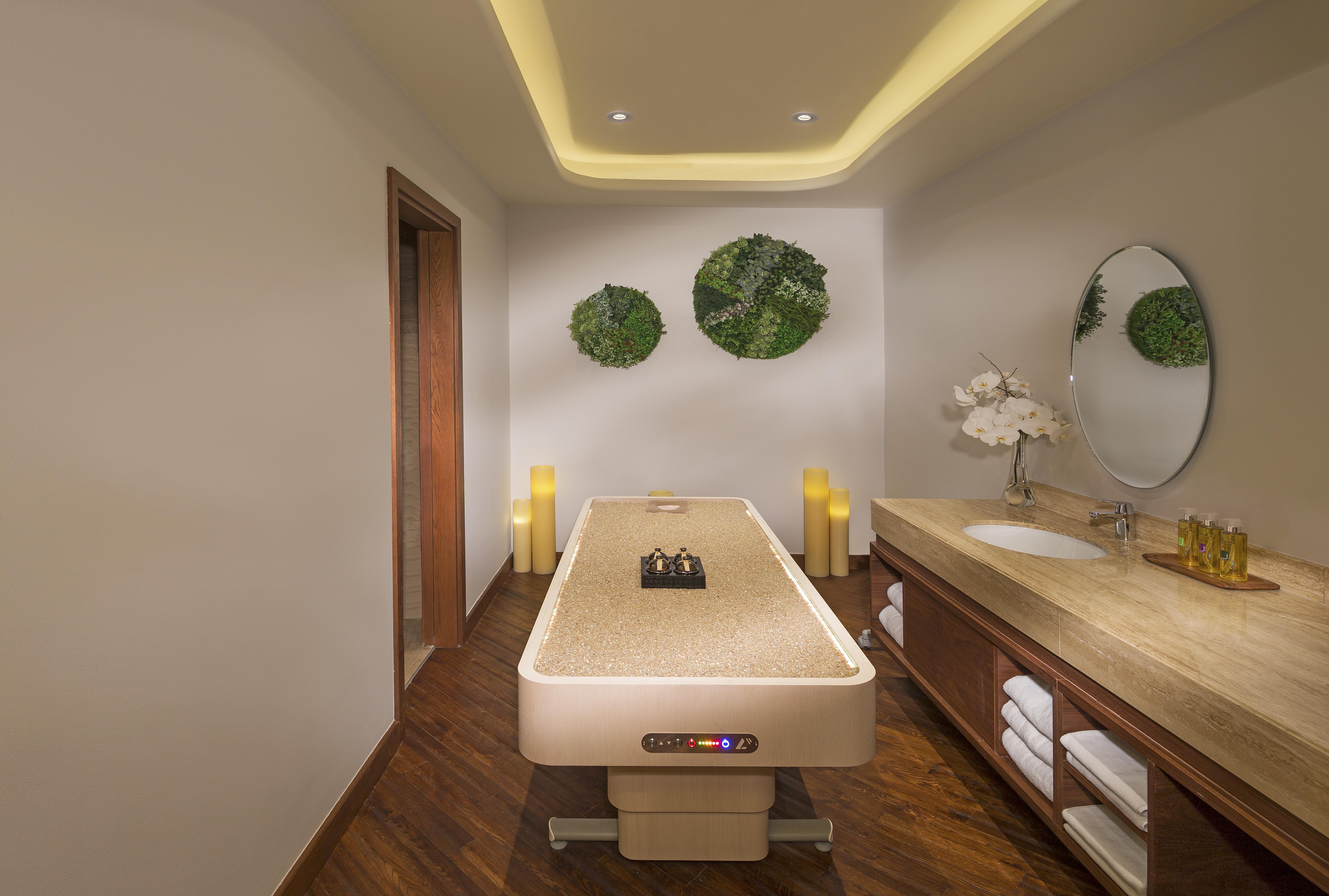 The Retreat Palm Dubai Mgallery By Sofitel Esterno foto The photo shows a serene spa room designed for relaxation and wellness. In the center, there is a massage table with a smooth surface, likely ready for treatments. The walls are decorated with round green wall art that appears to consist of natural m